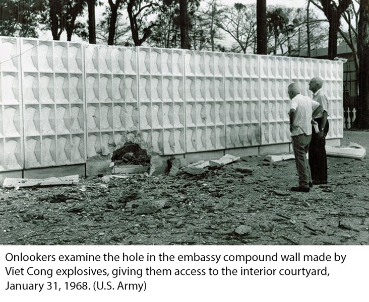 Onlookers examine the hole in the embassy compound wall made by Viet Cong explosives, giving them access to the interior courtyard, January 31, 1968. (U.S. Army)